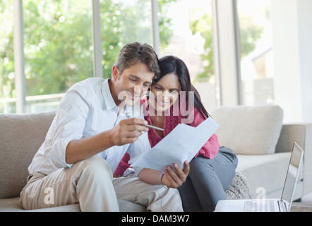 Accoppiare la lettura di fogli insieme sul divano Foto Stock