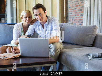 Paio utilizzando laptop insieme sul divano Foto Stock