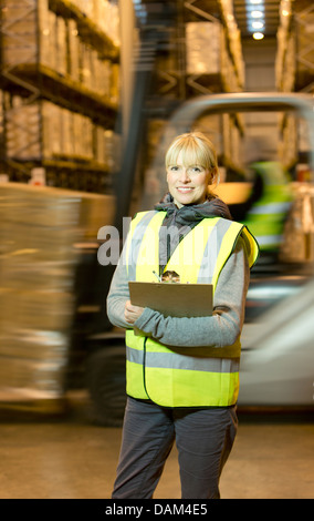 Lavoratore negli appunti di contenimento in magazzino Foto Stock