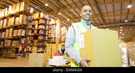 Lavoratore scatola portante in magazzino Foto Stock