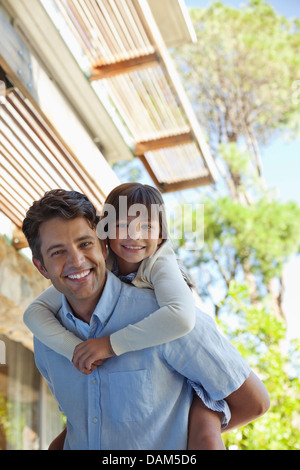 Padre figlia portante piggy back all'aperto Foto Stock