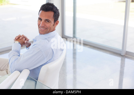 Imprenditore sorridente in sedia ufficio Foto Stock