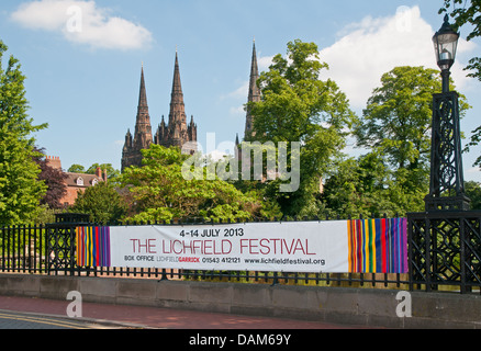 Banner pubblicitari di Lichfield Festival sul Minster ringhiere in piscina con le tre guglie di Lichfield Cathedral dietro Foto Stock