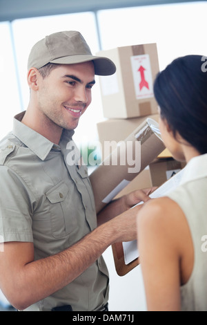 Ragazzo delle consegne con pacchetti per imprenditrice Foto Stock