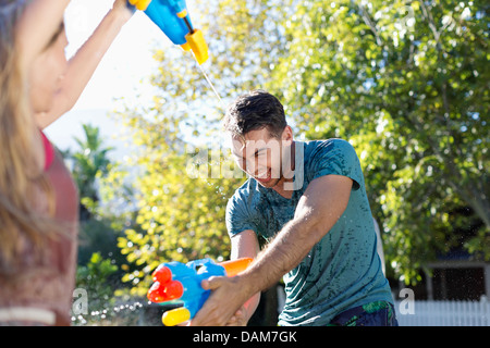 Giovane giocando con acqua pistole in cortile Foto Stock