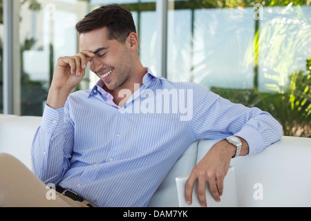 Imprenditore sorridente sul divano Foto Stock