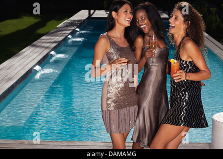 Le donne aventi le bevande con piscina Foto Stock