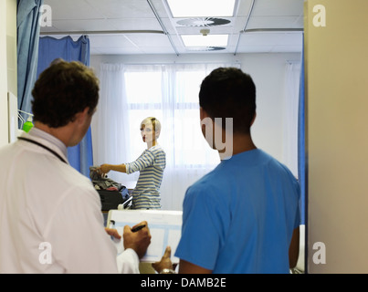 Medico e infermiere guardando la confezione del paziente nella stanza di ospedale Foto Stock