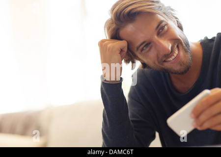 Uomo con cellulare sul divano Foto Stock