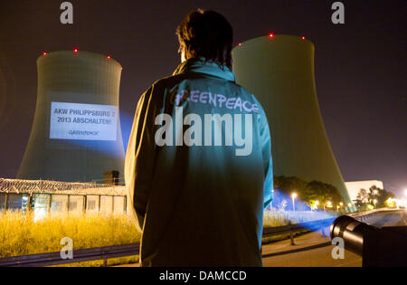 Un attivista del gruppo ambientalista Greenpeace sostare di fronte alla centrale nucleare, letterati 'chiudi centrale nucleare di Philippsburg 2 - 2013' sulle pareti dell'impianto di alimentazione, in Philippsburg, Germania, il 6 giugno 2011. Foto: Uwe Anspach Foto Stock