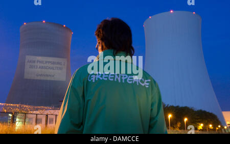 Un attivista del gruppo ambientalista Greenpeace sostare di fronte alla centrale nucleare, letterati 'chiudi centrale nucleare di Philippsburg 2 - 2013' sulle pareti dell'impianto di alimentazione, in Philippsburg, Germania, il 6 giugno 2011. Foto: Uwe Anspach Foto Stock