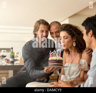 Donna che spegne le candeline sulla torta del compleanno Foto Stock