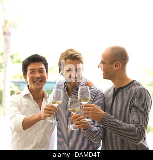 Gli uomini la tostatura a vicenda con il vino Foto Stock