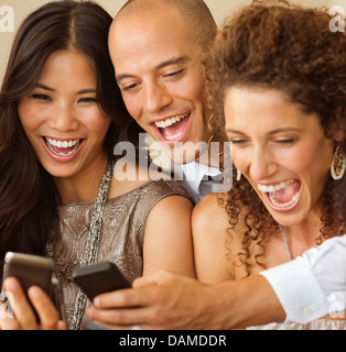 Gli amici utilizzando i telefoni cellulari insieme Foto Stock