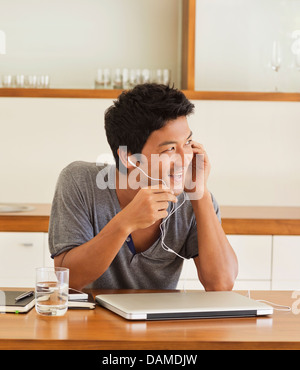 Uomo che indossa la cuffia a tavola Foto Stock