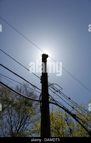 Una linea di alimentazione con il sole direttamente dietro la parte superiore del palo Foto Stock