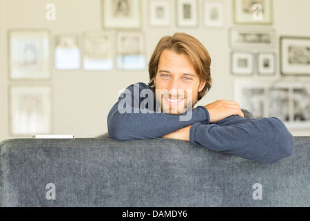 Uomo sorridente seduto sul divano Foto Stock
