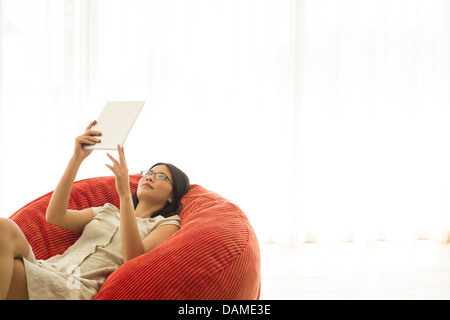 Donna che utilizza computer tablet in sedia beanbag Foto Stock