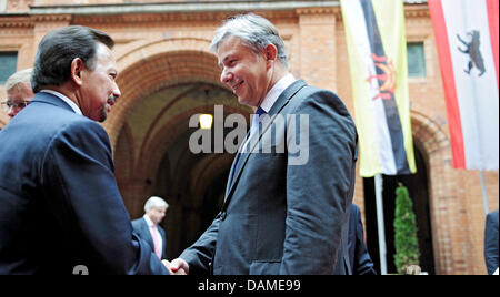 Sindaco di Berlino Klaus Wowereit (C) e il Sultano del Brunei, Haji Hassanal Bolkiah (L), salutare ogni altro nel cortile del rosso Municipio di Berlino, Germania, 08 giugno 2011. In background, sulla destra è la bandiera di Berlino e sulla sinistra è la bandiera del Brunei. Il Sultan è una politica della visita a Berlino. Foto: Annibale Foto Stock