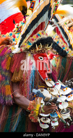 Uomo vestito in un colorato spirito ornamentali costume con una maschera rossa a Goroka Show in Papua Nuova Guinea Foto Stock