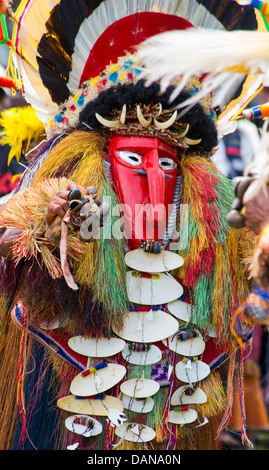 Uomo vestito in un colorato spirito ornamentali costume con una maschera rossa a Goroka Show in Papua Nuova Guinea Foto Stock