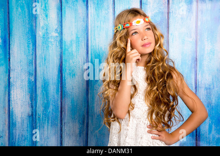 La bionda bambina pensando in blu vintage Sfondo legno Foto Stock