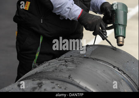 Un meccanico prepara pneumatici usati nel paddock presso il circuito di Silverstone nel Northamptonshire, Gran Bretagna, 08 luglio 2011. Il Gran Premio di Formula Uno di Gran Bretagna si svolgerà il 10 luglio 2011. Foto: David Ebener dpa Foto Stock
