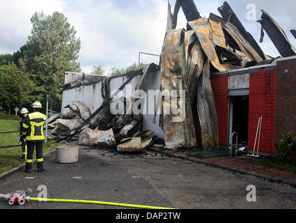 Due vigili del fuoco a stare di fronte ad una completamente bruciato down hall di un impianto sportivo in Oldenburg (Germania), 21 luglio 2011. Il fuoco è durato da mercoledì sera fino a giovedì mattina e ha distrutto una piscina, una sala sportiva e una zona benessere dell'impianto. La causa del fuoco è ancora poco chiaro. Foto: Ingo Wagner Foto Stock