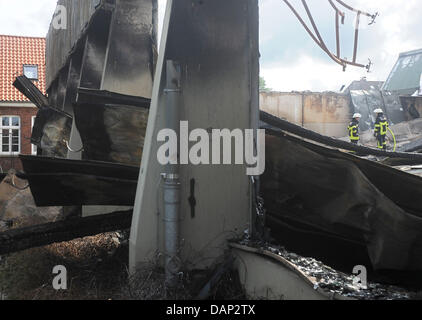 Due vigili del fuoco a stare di fronte ad una completamente bruciato down hall di un impianto sportivo in Oldenburg (Germania), 21 luglio 2011. Il fuoco è durato da mercoledì sera fino a giovedì mattina e ha distrutto una piscina, una sala sportiva e una zona benessere dell'impianto. La causa del fuoco è ancora poco chiaro. Foto: Ingo Wagner Foto Stock