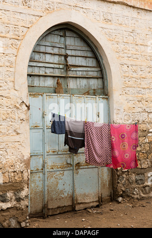 Africa, Eritrea, Massaua, Città Vecchia, lavaggio appeso sulla linea esterno dipinto di blu ottomano porta ad arco Foto Stock