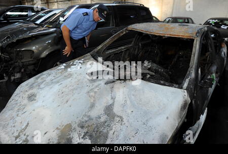 Funzionario di polizia Stefan Pedersen guarda un bruciato auto presso la polizia del veicolo area depositaria di Berlino, Germania, 18 agosto 2011. Più di 30 auto bruciata a Berlino in tre notti consecutive. Foto: Tim Brakemeier Foto Stock