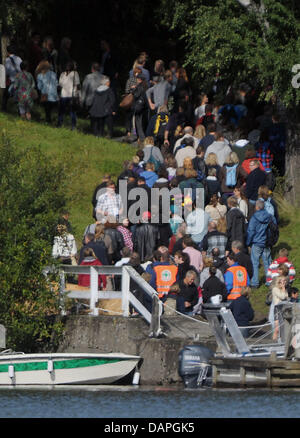 I superstiti del massacro di Utoya e i loro parenti arrivano su una barca sull'isola di Utoya, Norvegia, 20 agosto 2011. Quattro settimane dopo l'esplosione di bomba a Oslo e il successivo massacro in un campo di vacanze sull'isola di Utoya, Norvegia commemora il 77 vittime dell attacco con una tre giorni di memoriale di servizio. Foto: Hannibal Hanschke Foto Stock