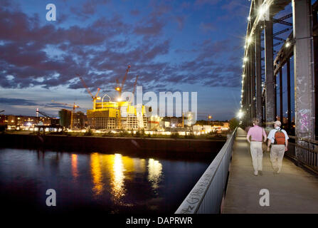 Due pedoni a piedi il ponte della ferrovia Deutschherrnbruecke (R) e guardare al illuminato sito in costruzione per la nuova sede della Banca centrale europea BCE a Francoforte sul Meno, Germania, 22 agosto 2011. Il cosiddetto Skytower deve essere completato nel 2014. La Banca centrale europea è la costruzione della sua nuova sede sulla ex Großmarkthalle (mercato all'ingrosso) sito. Ph Foto Stock