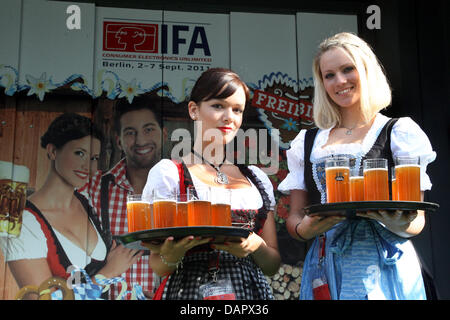 Due hostess offrono la birra all'interno del più piccolo al mondo 'Oktoberfest' birra tenda all'apertura dell'IFA 2011 fiera di elettronica di consumo ed elettrodomestici a Berlino, Germania, 02 settembre 2011. I visitatori possono sedersi sulle panchine all'interno di un materiale sollevare (indietro) nella hall 5, gustare una birra e di essere elevata ad altri luoghi espositivi. L' IFA apre le sue porte a partire dal 2 settembre 2011 al 7 S Foto Stock