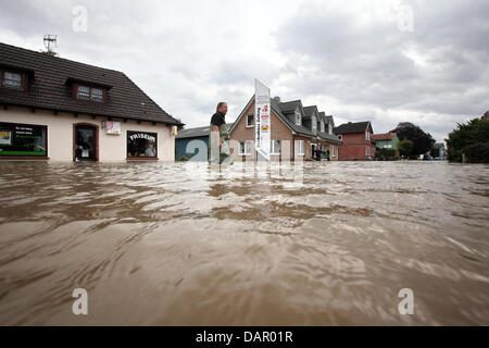 Un uomo cammina attraverso l acqua in un invaso street in Gelting, Germania, 06 settembre 2011. La condizione di inondazioni in Gelting ha solo attenuato un po' il martedì e i collaboratori sono in funzionamento. Il dipartimento dei vigili del fuoco e THW (Agenzia Federale di soccorso tecnico) sta tentando di master di acqua, che è sceso sul villaggio durante le piogge di domenica, con pompe. Foto: BODO SEGNA Foto Stock