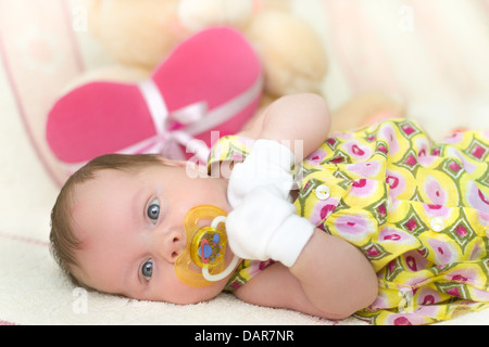 Infant Baby girl (1 mese fa) giacente sul letto con Teddy bear Foto Stock