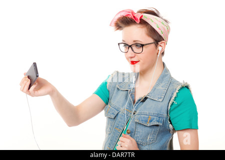 Ragazza adolescente, vestito casualmente, pose tenendo un iphone per ascoltare musica e parlare al telefono e di scattare foto di se stessa. Foto Stock