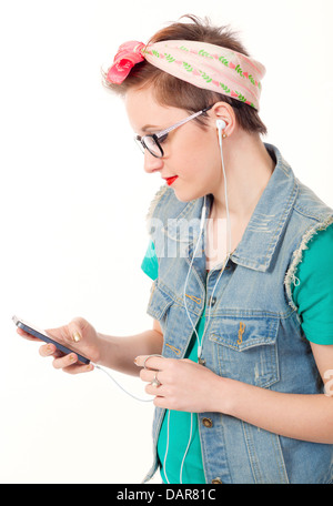 Ragazza adolescente, vestito casualmente, pose tenendo un iphone per ascoltare musica e parlare al telefono e di scattare foto di se stessa. Foto Stock