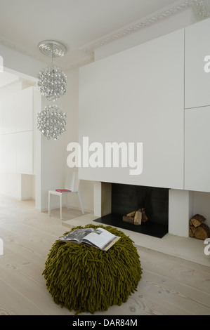 Bianco stanza vivente con un pallido pavimenti in legno, luce di dichiarazione di Verner Panton e pouf verde di Nicole Farhi Foto Stock