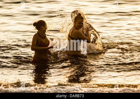 Aberystwyth Wales UK, mercoledì 17 luglio 2013. Tre donne giocando in mare in Aberystwyth, su Cardigan Bay sulla costa occidentale del Galles UK, stagliano contro il sole di setting alla fine di un altro caldo secco giornata di sole la magia di alta pressione, con fine secco sole e temperature nella media-alta 20's celsius, è impostata per continuare per una settimana o dieci giorni, segnando il più lungo periodo di buona estate meteo nel Regno Unito per molti anni. Photo credit: keith morris/Alamy Live News Foto Stock