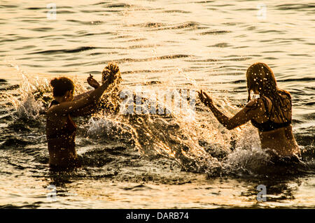 Aberystwyth Wales UK, mercoledì 17 luglio 2013. Tre donne giocando in mare in Aberystwyth, su Cardigan Bay sulla costa occidentale del Galles UK, stagliano contro il sole di setting alla fine di un altro caldo secco giornata di sole la magia di alta pressione, con fine secco sole e temperature nella media-alta 20's celsius, è impostata per continuare per una settimana o dieci giorni, segnando il più lungo periodo di buona estate meteo nel Regno Unito per molti anni. Photo credit: keith morris/Alamy Live News Foto Stock