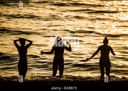 Aberystwyth Wales UK, mercoledì 17 luglio 2013. Tre donne giocando in mare in Aberystwyth, su Cardigan Bay sulla costa occidentale del Galles UK, stagliano contro il sole di setting alla fine di un altro caldo secco giornata di sole la magia di alta pressione, con fine secco sole e temperature nella media-alta 20's celsius, è impostata per continuare per una settimana o dieci giorni, segnando il più lungo periodo di buona estate meteo nel Regno Unito per molti anni. Photo credit: keith morris/Alamy Live News Foto Stock