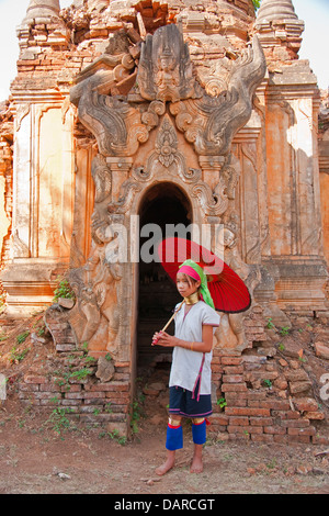 Giovane ragazza Padaung con portale intagliato di antico stupa in rovine vicino Indein villaggio sul Lago Inle, Stato Shan, Myanmar. Foto Stock