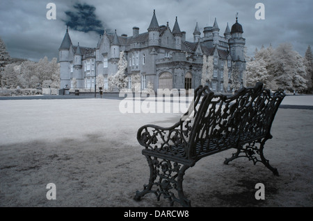 Immagine infrarossa del castello di Balmoral, Scozia con panchina da giardino in primo piano. hrh Queen Elizabeth e famiglia trascorrono l'estate qui. Foto Stock