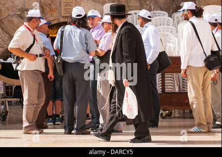 Israele Gerusalemme vecchia città pianto Muro occidentale ha Kotel Plaza gruppo turistico di adoratori ebrei guardato da ultra ortodosso Hassid a piedi Tzitzit barba Foto Stock