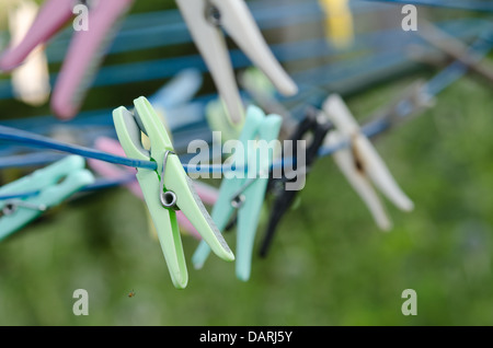 Fila di vecchia nuova plastica legno mollette su una linea di lavaggio con fuori fuoco sfondo pronto per il lavaggio di un quotidiano chore Foto Stock