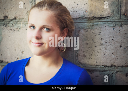 Giovani blue-eyed girl vicino a un muro di mattoni Foto Stock