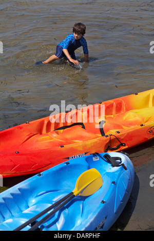 Giovane ragazzo in mare con il kayak colorati a barene, Poole, Dorset in luglio Foto Stock