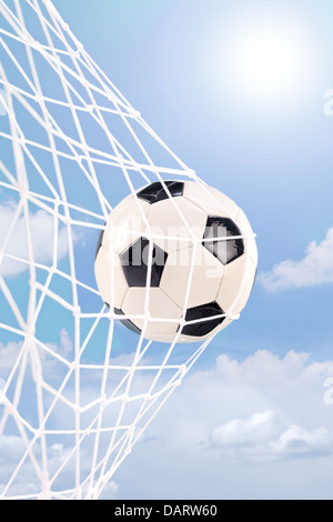 Pallone da calcio in un gol contro il cielo nuvoloso Foto Stock