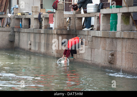 Cina, periferia di Shanghai. Acqua di antico villaggio di Zhujiajiao (aka perla Stream). Donna pan di lavaggio nel canale. Foto Stock